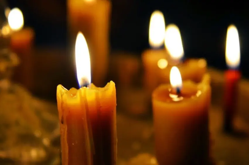 Antique candle burning in a dark room. Christmas Eve, divination, yuletide. Christmas backgrounds. holiday rituals, religion, spirituality, zen. space for text, close-up, copy space.