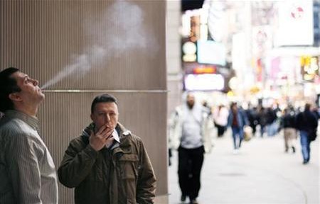 A pair of smokers stand outside of an office building