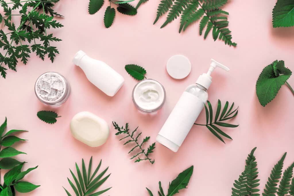 Natural,Cosmetics,And,Green,Leaves,On,Pink,Background,,Top,View,