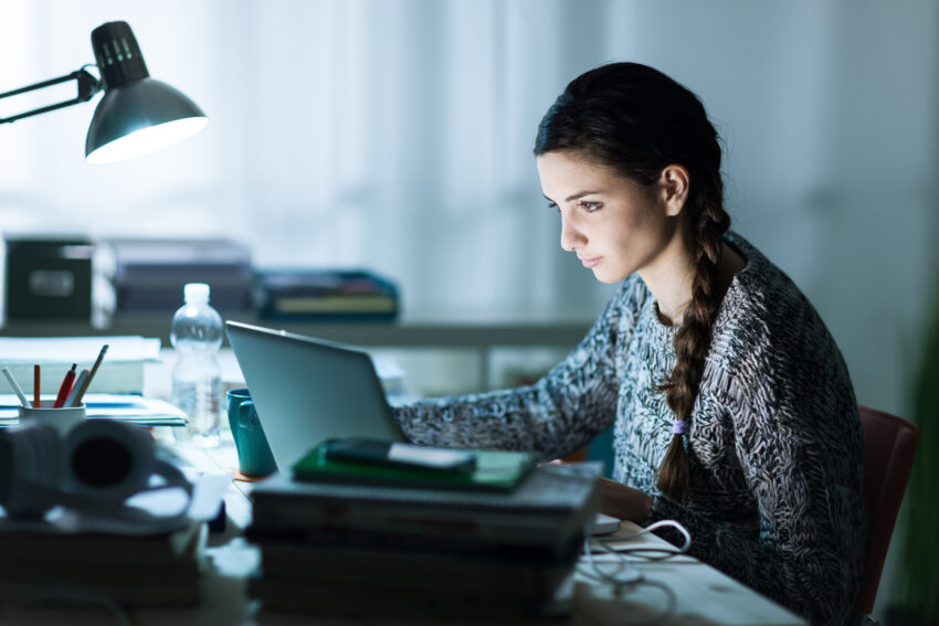Pretty,Young,Student,Sitting,At,Desk,And,Doing,Her,Homework,