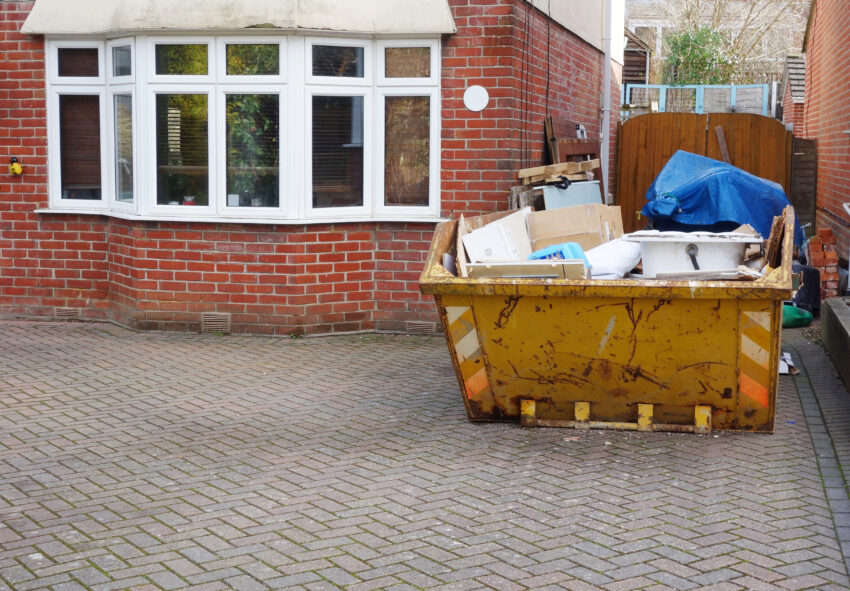 Full,Industrial,Rubbish,Bin,On,Driveway,In,Front,Of,Brick