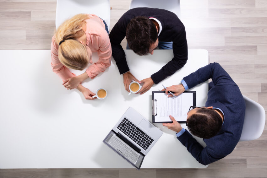 Happy,Young,Couple,Consulting,Male,Friendly,Financial,Advisor,With,Coffee
