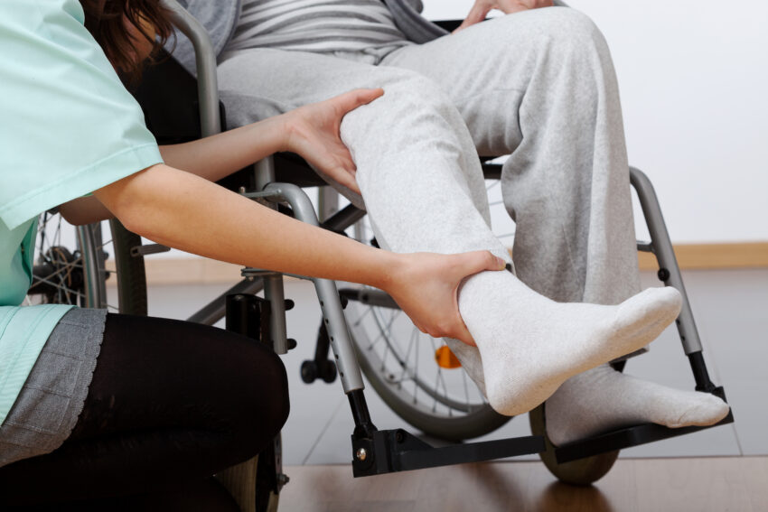 Young,Physiotherapist,Exercising,With,Elder,Disabled,Person