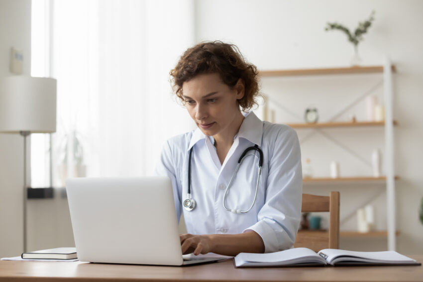 Serious,Woman,Wearing,White,Uniform,With,Stethoscope,Working,On,Laptop,