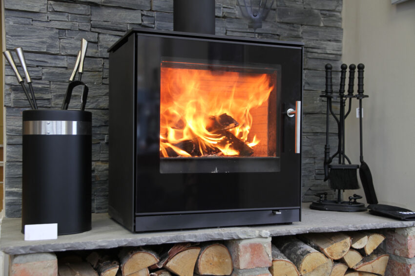 Black,Modern,Looking,Wood,Burning,Stove,With,Logs,Underneath
