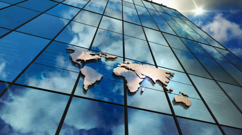 World,Map,Sign,On,Glass,Skyscraper.,Sky,And,Sun,Rays