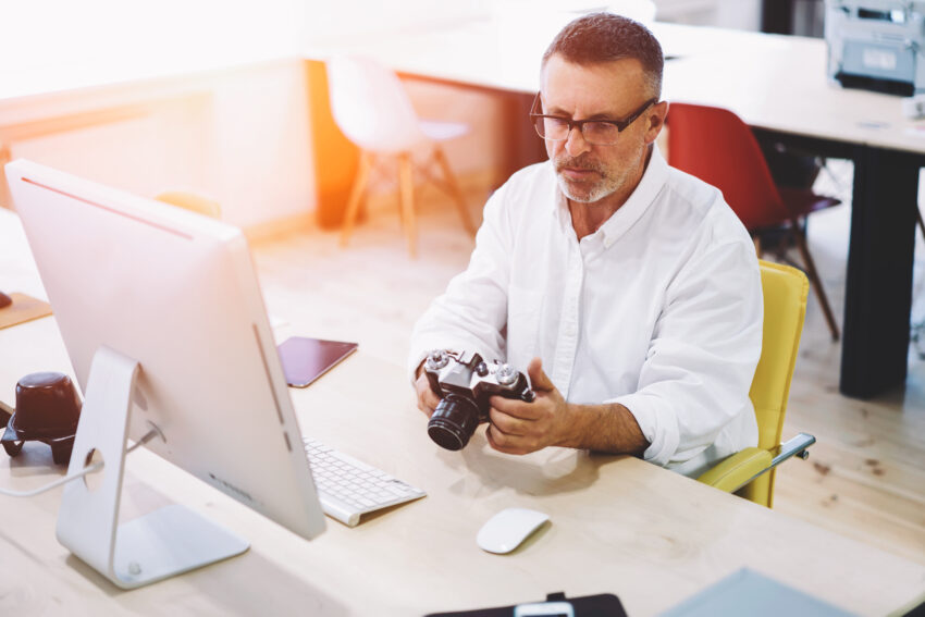 Male programmer 50 years old looking picture made by colleague a