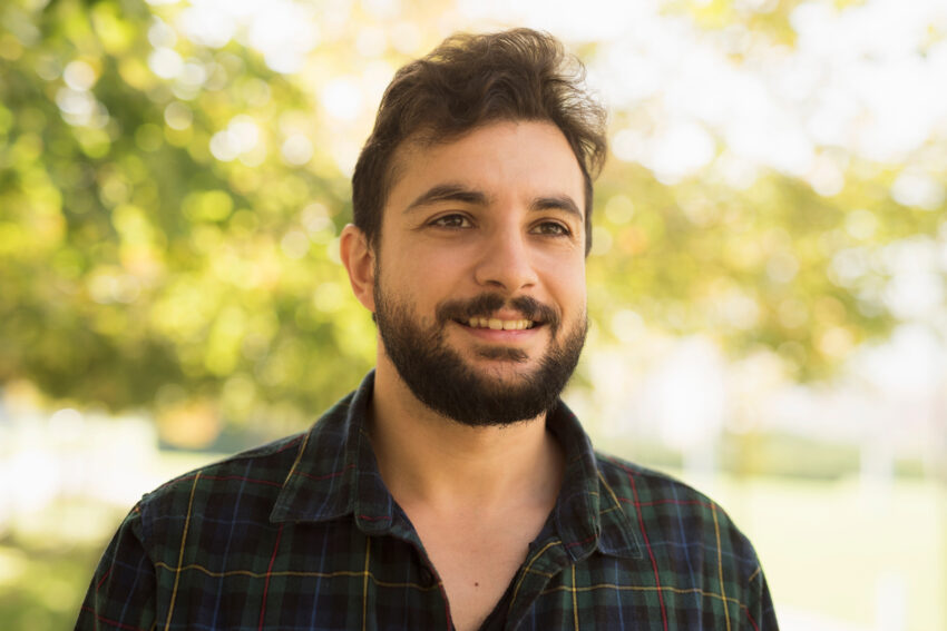 Bearded man in outdoors park. Smiling disheveled