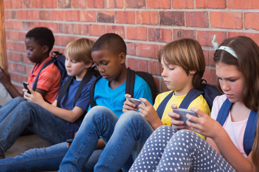 Cute,Pupils,Using,Mobile,Phone,At,The,Elementary,School