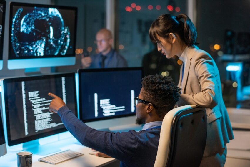 Confident,Businessman,Pointing,At,Coded,Data,On,Computer,Screen,While